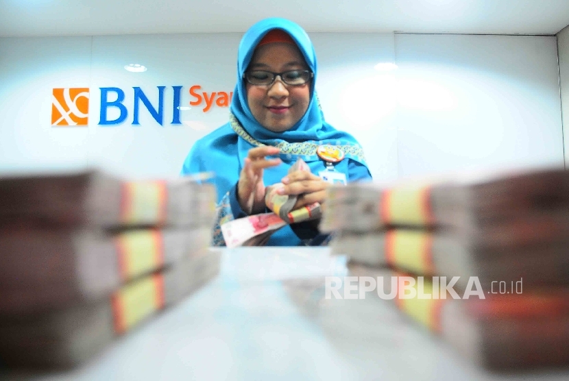 Karyawati menghitung uang di banking Hall bank BNI Syariah, Jakarta, Senin (23/1).