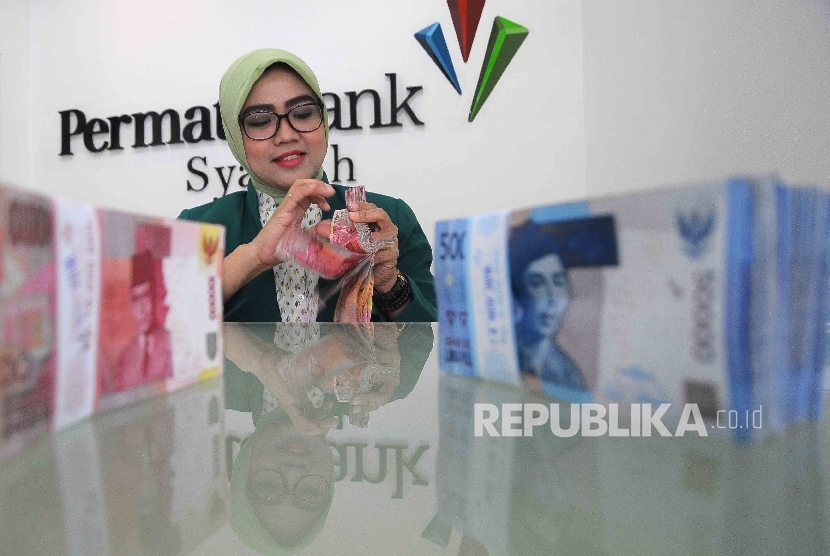  Karyawati menghitung uang di Banking Hall Bank Permata Syariah, Jakarta, Senin (2/1).