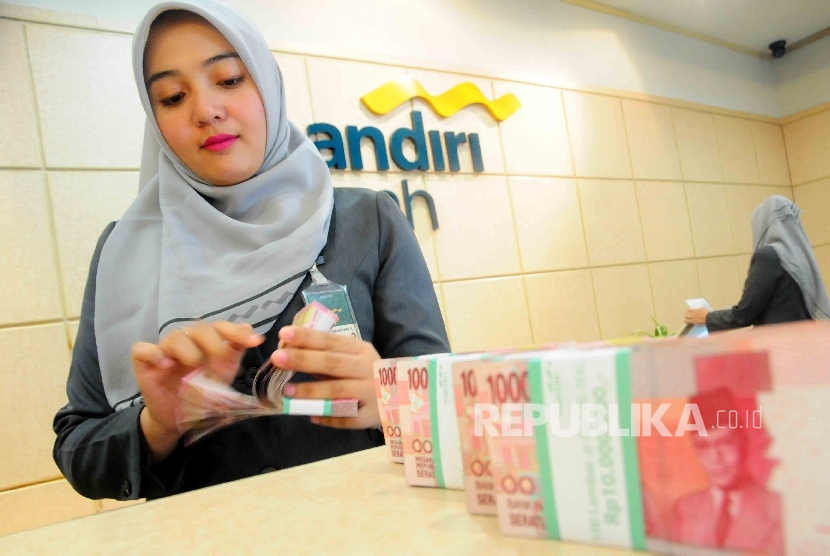 Karyawati menghitung uang di Banking Hall Bank Syariah Mandiri, Jakarta. (ilustrasi) 