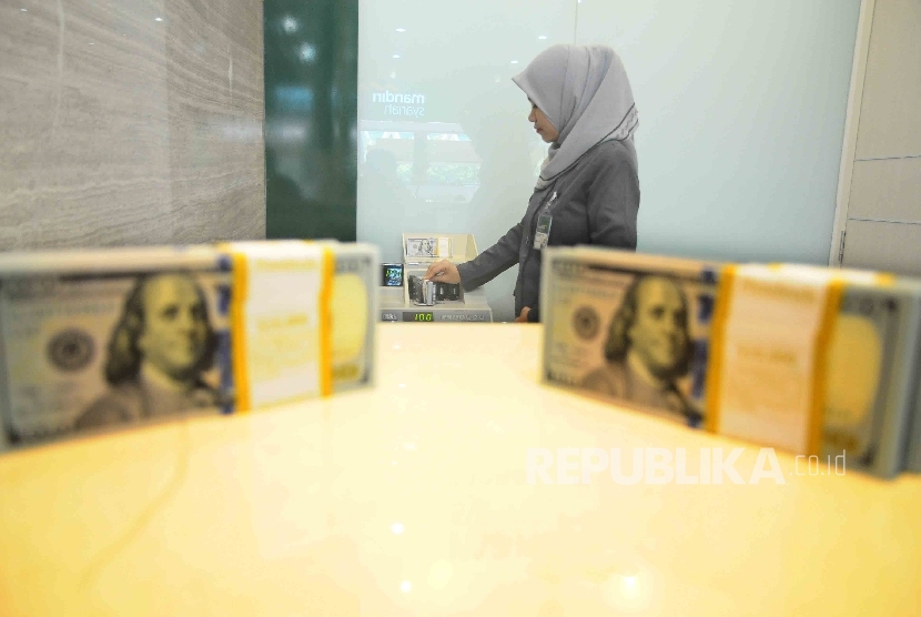 Karyawati menghitung uang dolar AS di tempat penukaran uang Bank Mandiri Syariah, Jakarta, Kamis (20/10). 