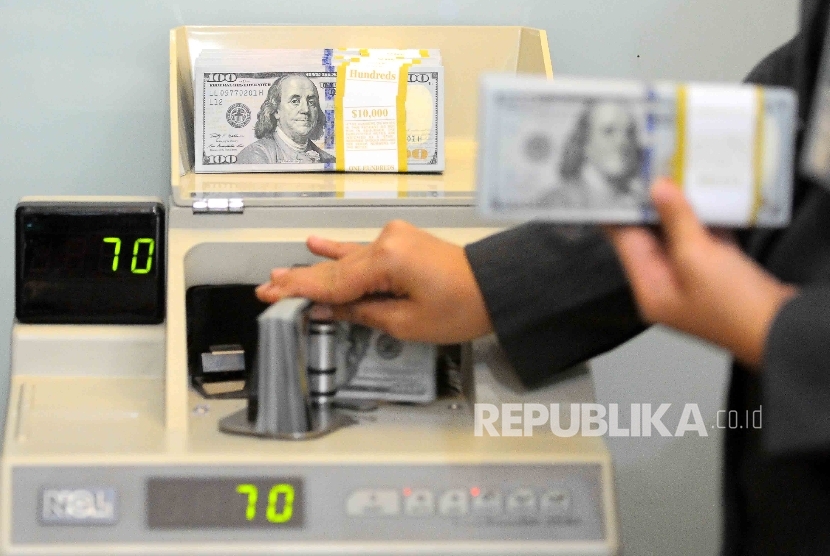 Karyawati menghitung uang dolar AS di tempat penukaran uang Bank Mandiri Syariah, Jakarta.