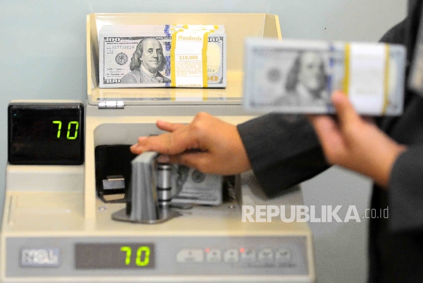 Karyawati menghitung uang dolar AS di tempat penukaran uang Bank Mandiri Syariah, Jakarta, Kamis (20/10).