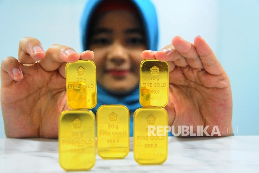  Karyawati menunjukan emas batangan di Banking Hall Bank BNI Syariah, Jakarta, Selasa (23/5). 