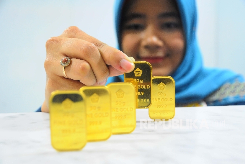  Karyawati menunjukan emas batangan. Direktur PT Solid Gold Berjangka Dikki Soetopo mengatakan pasar saham, termasuk perdagangan emas dunia mengalami lonjakan yang cukup tajam