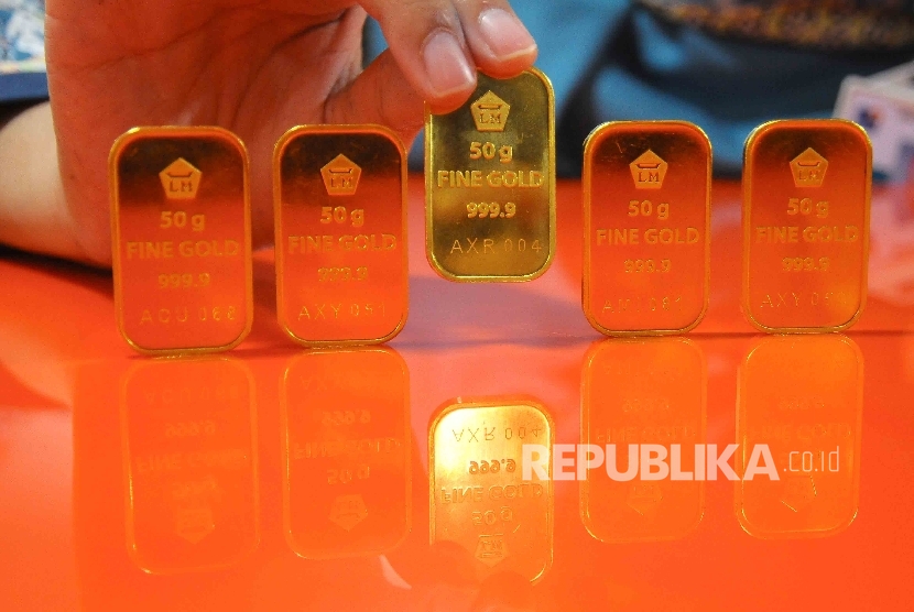  Karyawati menunjukan emas batangan disalah satu bank di Jakarta, Jumat (9/12).(Republika/Agung Supriyanto)