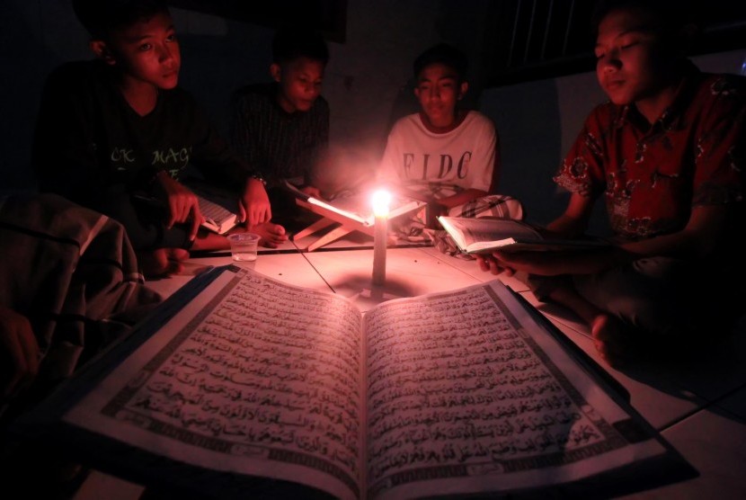 Kaum musllim membaca Alquran dengan penerangan lilin saat listrik padam di Desa Meunasah Alue, Muara Dua, Lhokseumawe, Aceh, Jumat (9/6) dini hari. 