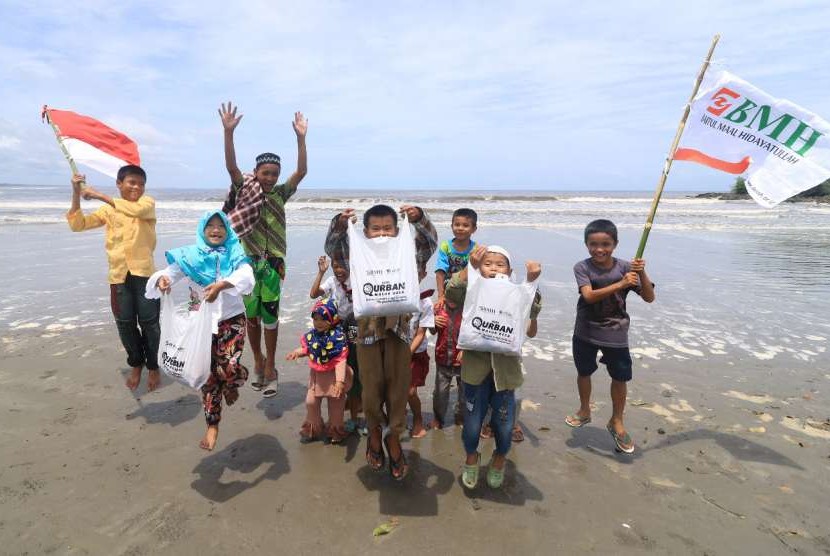 Kebahagiaan anak-anak Desa Faekhuna'a Afulu membawa paket daging kurban BMH di tepi pantai.