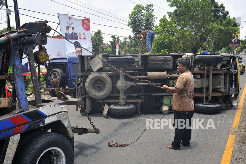 Petugas derek berupaya mengevakuasi truk yang terguling. (Ilustrasi)