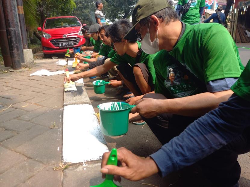 Kegiatan aksi sosial pengecetan separator yang sudah kusam di Jalan Pintu 2 Taman Mini, Kecamatan Cipayung, Jakarta Timur.