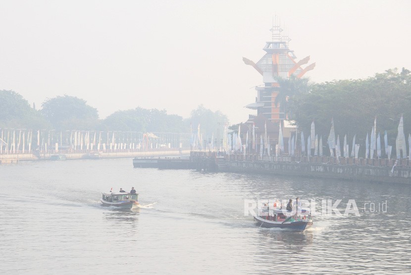 Kelotok (perahu bermesin) melintas di Sungai Martapura yang diselimuti kabut asap di Kota Banjarmasin, Kalimantan Selatan, Kamis (5/9/2019). 