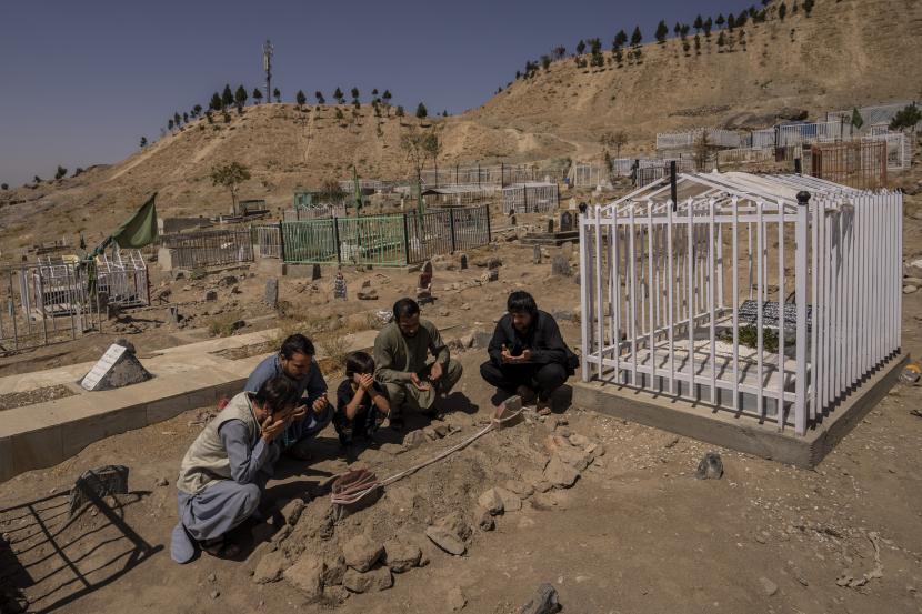 Keluarga Ahmadi berdoa di pemakaman di sebelah makam keluarga anggota keluarga yang terbunuh oleh serangan pesawat tak berawak AS di Kabul, Afghanistan, Senin, 13 September 2021.