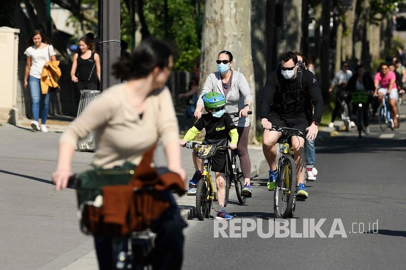 Keluarga dengan mengenakan masker wajah bersepeda pada akhir pekan pertama setelah dua bulan diberlakukannya lockdown di Paris, Prancis,Ahad (17/5). Prancis mulai melongarkan lockdown secara bertahap di tengah pandemi COVID-19.  