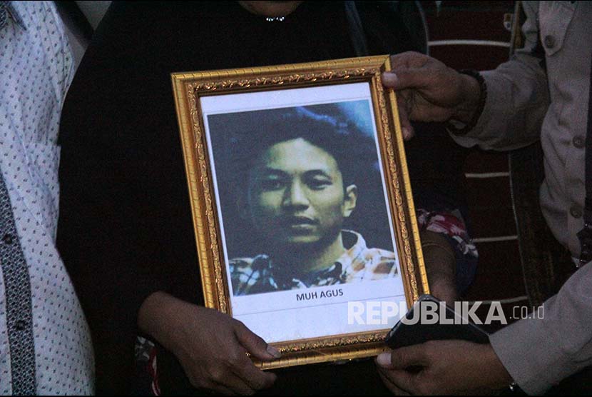 Keluarga korban penembakan kelompok kriminal bersenjata (KKB) memegang foto Muhammad Agus saat jenazah tiba di Landasan Udara Hasanuddin, Kabupaten Maros, Sulawesi Selatan, Jumat (7/12)
