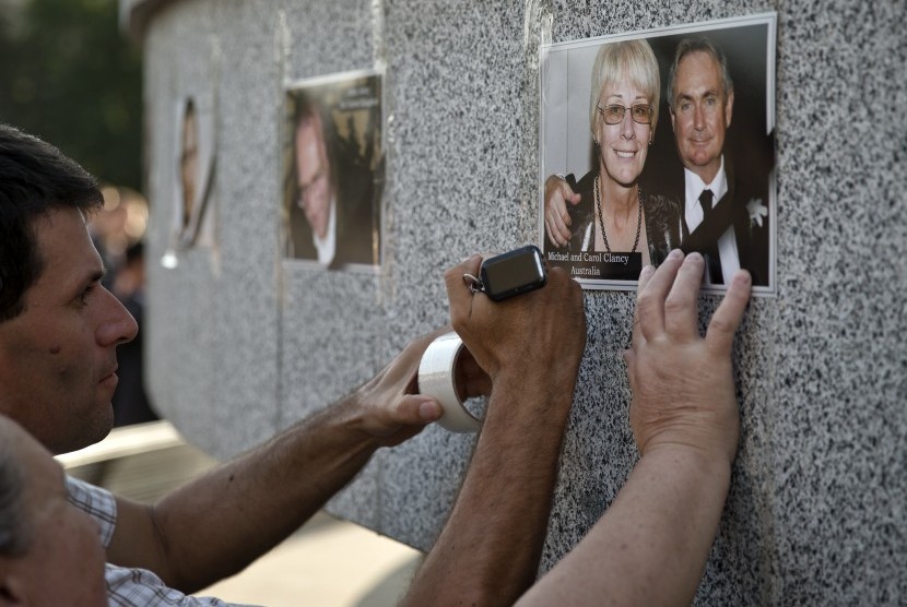 Keluarga korban pesawat Malaysia Airlines MH17 yang jatuh menempel foto kerabat mereka di dinding memorial di Kharkiv, Ukraina, Kamis (24/7).