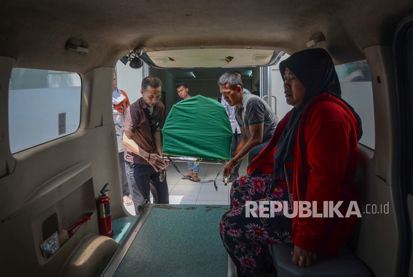 Keluarga membawa jenazah korban meninggal akibat keracunan minuman keras (miras) oplosan ke dalam mobil ambulans di Rumah Sakit Umum Daerah (RSUD) Cicalengka, Kabupaten Bandung, Jawa Barat, Senin (9/4).