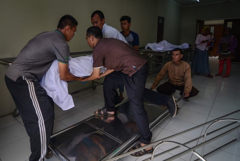 Keluarga memindahkan jenazah korban meninggal akibat keracunan minuman keras (miras) oplosan ke dalam mobil ambulans di Rumah Sakit Umum Daerah (RSUD) Cicalengka, Kabupaten Bandung, Jawa Barat, Senin (9/4). 