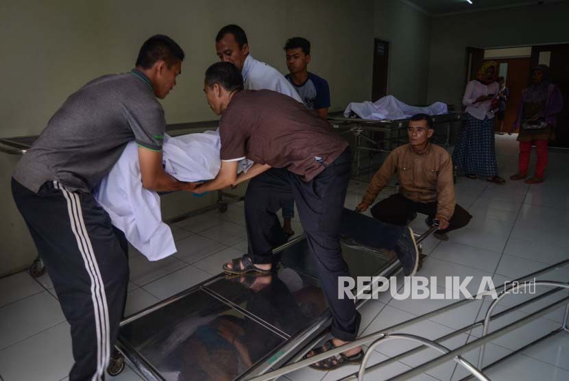 Keluarga memindahkan jenazah korban meninggal akibat keracunan minuman keras (miras) oplosan ke dalam mobil ambulans di Rumah Sakit Umum Daerah (RSUD) Cicalengka, Kabupaten Bandung, Jawa Barat, Senin (9/4). 