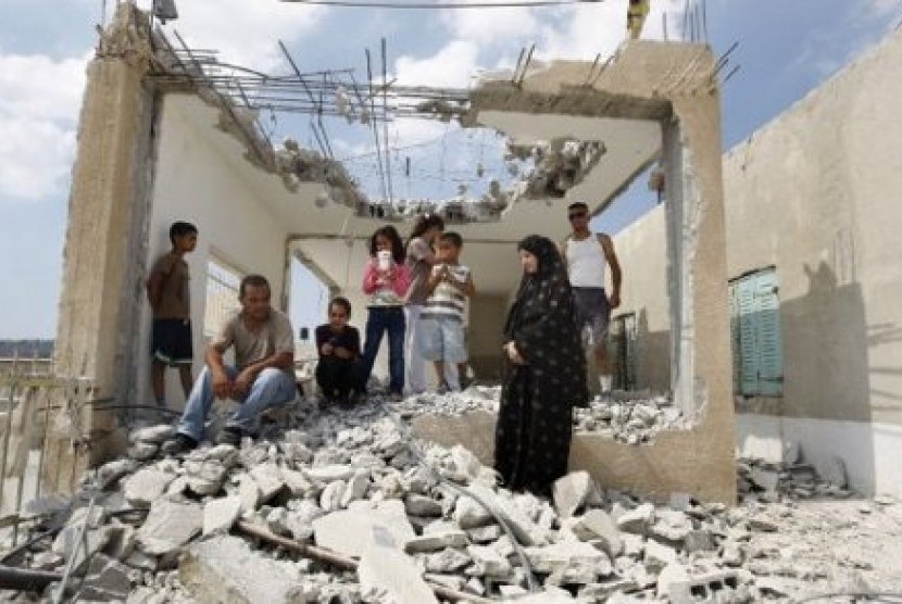 Keluarga Palestina di tengah puing bangunan tempat tinggal mereka yang dihancurkan oleh Israel
