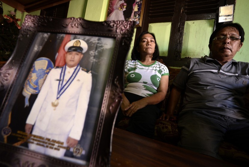 Keluarga WNI yang disandera kelompok Abu Sayyaf, Agustin Pilohoma (50) dan Jemmy Repi (58) duduk di belakang foto putranya, Alfian Elvis Repi, di kediaman mereka di Desa Kauditan, Minahasa Utara, Sulawesi Utara, Rabu (6/4).