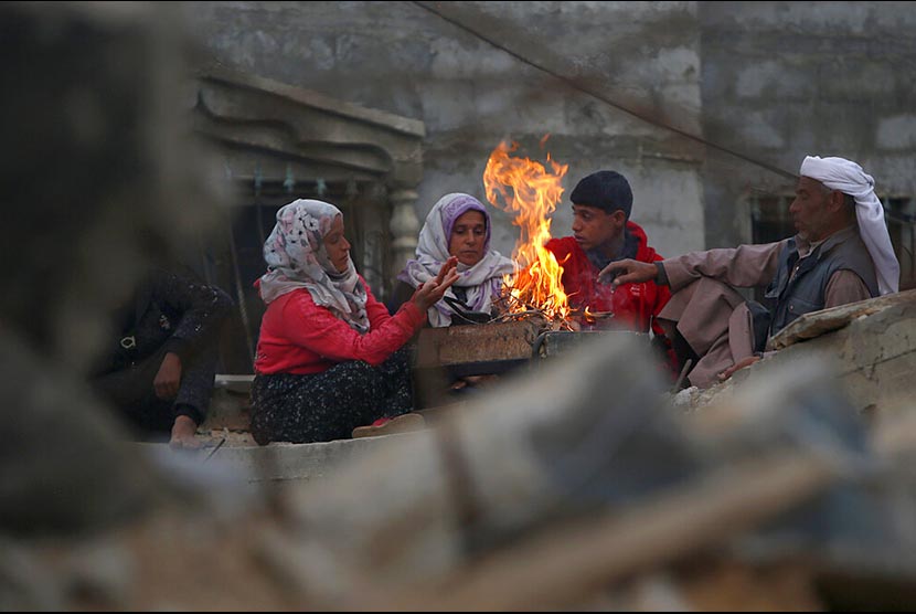 Kelurga Hamouda Abu Amra berkumpul mengelilingi api unggun untuk mengusir dingin tidak jauh dari kediaman mereka yang  di Khan Younis, selatan Jalur Gaza. Bangunan 5 lantai yang dihuni 19 jiwa itu hancur dibombardir serangan udara Israel pada  November tahun lalu.