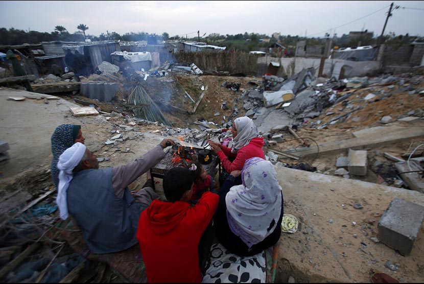 PBB Cemaskan Kondisi Hidup Masyarakat Palestina. Kelurga Hamouda Abu Amra berkumpul mengelilingi api unggun untuk mengusir dingin tidak jauh dari kediaman mereka yang  di Khan Younis, selatan Jalur Gaza. Bangunan 5 lantai yang dihuni 19 jiwa itu hancur dibombardir serangan udara Israel November tahun lalu.