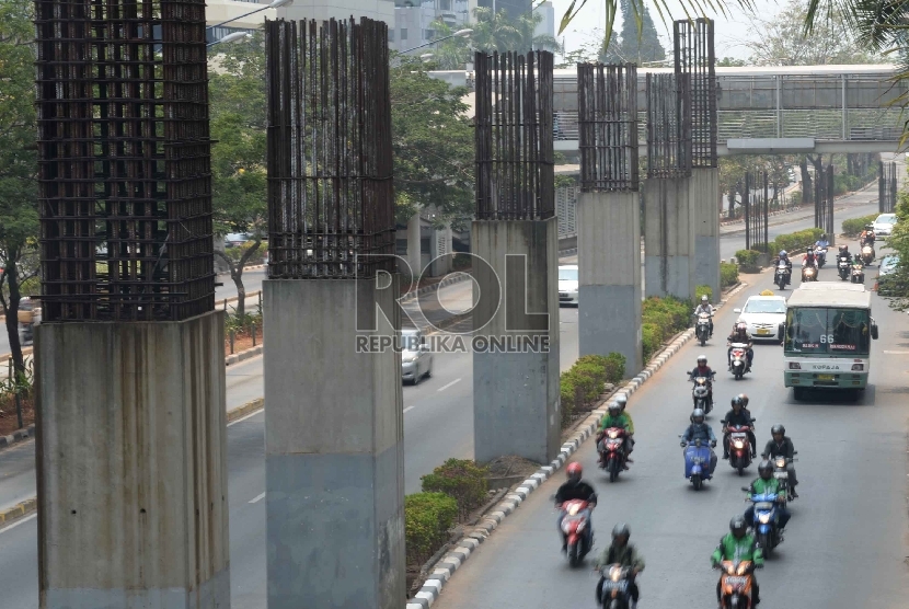 Kendaraan berjalan di samping konstruksi tiang proyek monorel yang terbengkalai di Kawasan Kuningan, Jakarta, Jumat (11/9). 