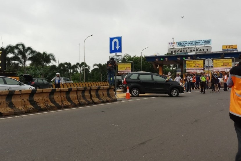 Kendaraan berpelat nomor ganjil memutar arah karena tak boleh memasuki Gerbang Tol Bekasi Barat 1 pada hari pertama penerapan aturan pelat nomor ganjil-genap di Bekasi, Senin (12/3).