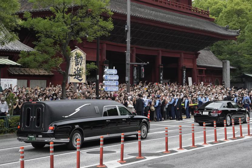  Kendaraan (kiri) membawa jenazah mantan Perdana Menteri Jepang Shinzo Abe meninggalkan kuil Zojoji setelah pemakamannya di Tokyo pada Selasa, 12 Juli 2022. Abe dibunuh Jumat saat berkampanye di Nara, Jepang barat. 