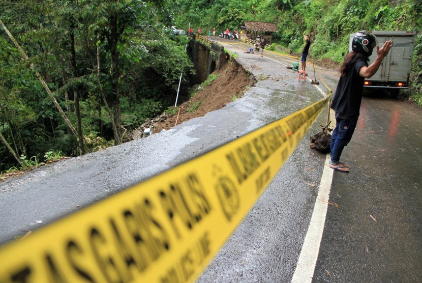 Kendaraan melintas di jalan nasional yang longsor di Desa Sawahan, Trenggalek, Jawa Timur, Jumat (9/9).