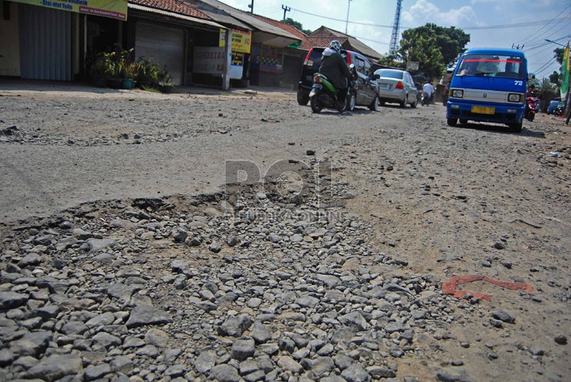  Kendaraan melintas di Jalan Raya Kampung Sawah yang rusak parah, Depok, Jumat (1/8). (Republika/Raisan Al Farisi)