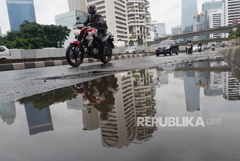 Kendaraan melintas di samping genangan air di Jalan Sudirman, Jakarta Pusat, Senin (1/2).