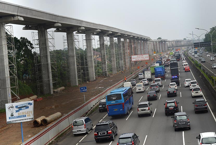 Kendaraan melintas di samping pembangunan  proyek Light Rail Transit (LRT) di Cibubur, Jaktim, Selasa (14/2). 