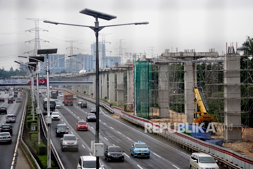 Kendaraan melintas di samping proyek infrastruktur transportasi massal kereta ringan atau Light Rail Transit (LRT) di kawasan Halim, Jakarta, Jumat (30/6). 