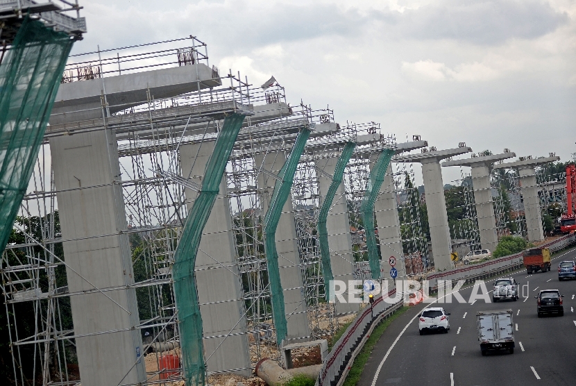 Kendaraan melintas di samping proyek pembangunan tiang penyangga jalur transportasi Light Rail Transit (LRT) rute Cibubur-Cawang di kawasan Halim, Jakarta, Selasa (7/2)