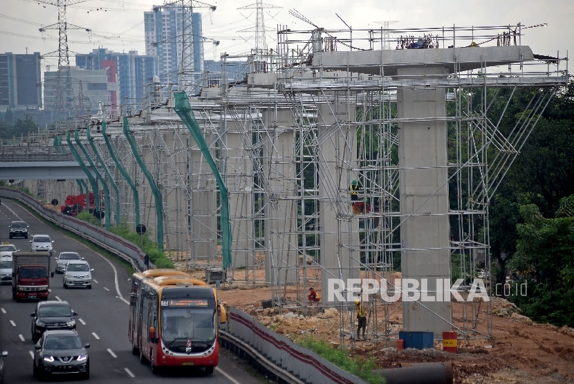 Kendaraan melintas di samping proyek pembangunan tiang penyangga jalur transportasi Light Rail Transit (LRT) rute Cibubur-Cawang di kawasan Halim, Jakarta, Selasa (7/2).