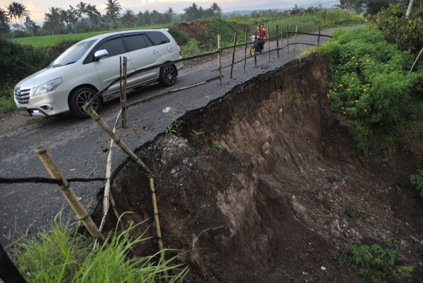 Kendaraan melintasi sebagian badan jalan yang longsor di Nagari Barulak, Kab. Tanah Datar, Sumatera Barat, Jumat (31/3). 