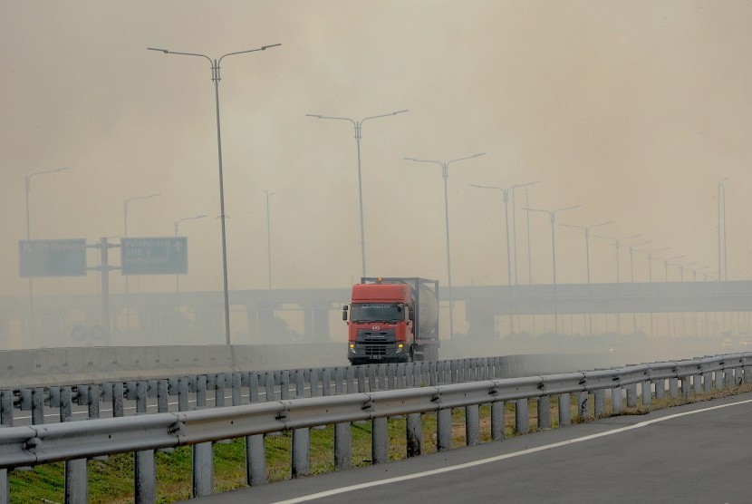 Kendaraan menerobos kabut asap akibat kebakaran lahan di tol Palembang-Indralaya, Sumatera Selatan, Rabu (7/8/2019). 
