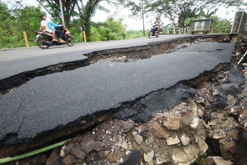 Kendaraan roda dua melintas disamping ruas jalan yang ambrol (ilustrasii) 