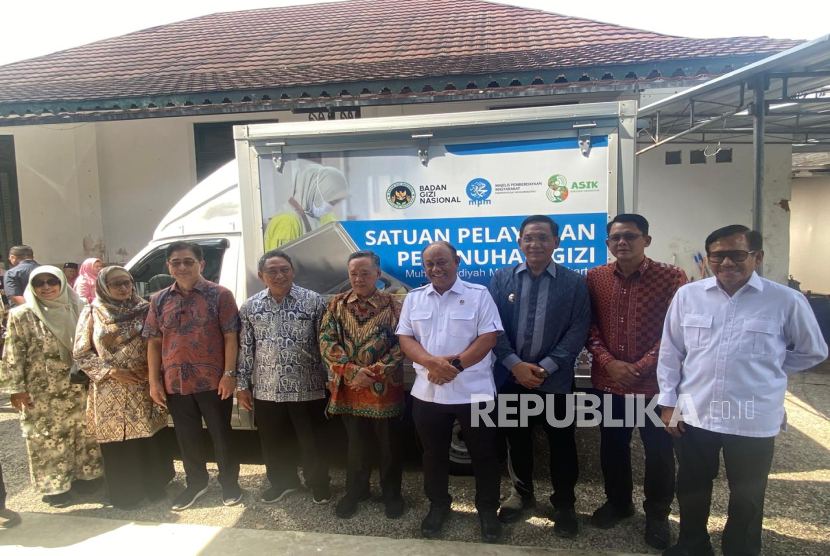 Kepala Badan Gizi Nasional (BGN) RI Dadan Hindayana (tengah, baju putih) berfoto bersama para pimpinan Muhammadiyah dan pejabat lokal di DIY usai mengunjungi SPPG Muhammadiyah Minggir, Kabupaten Sleman, Yogyakarta, Selasa (15/7/2025).  