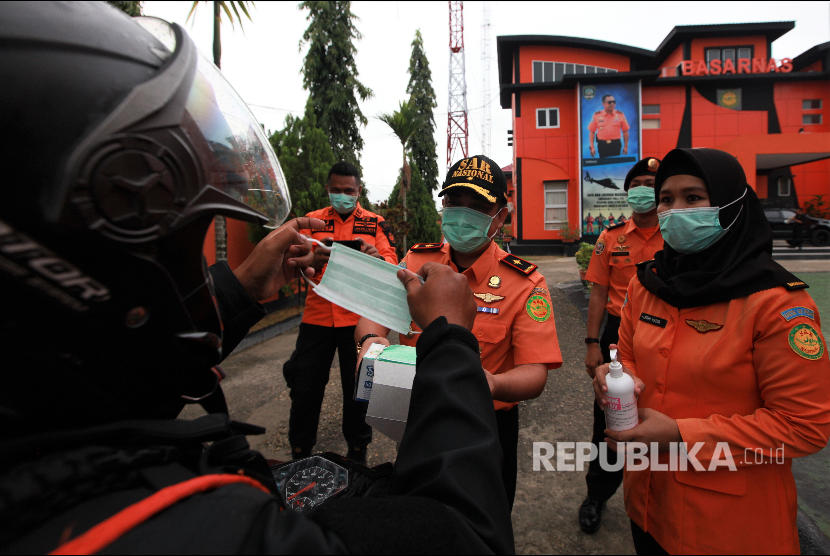 Kepala Basarnas Kendari Aris Sofingi (tengah) memberikan masker kepada personelnya yang hendak bekerja di luar kantor di Kantor Basarnas Kendari, Kendari, Sulawesi Tenggara, Senin (9/3).