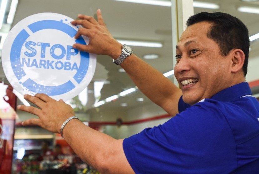 Kepala BNN Komjen Pol Budi Waseso menempelkan  Stiker Stop Narkoba di dinding salah satu mini market di Surabaya, Jawa Timur, Kamis (26/11). (Antara/Zabur Karuru)