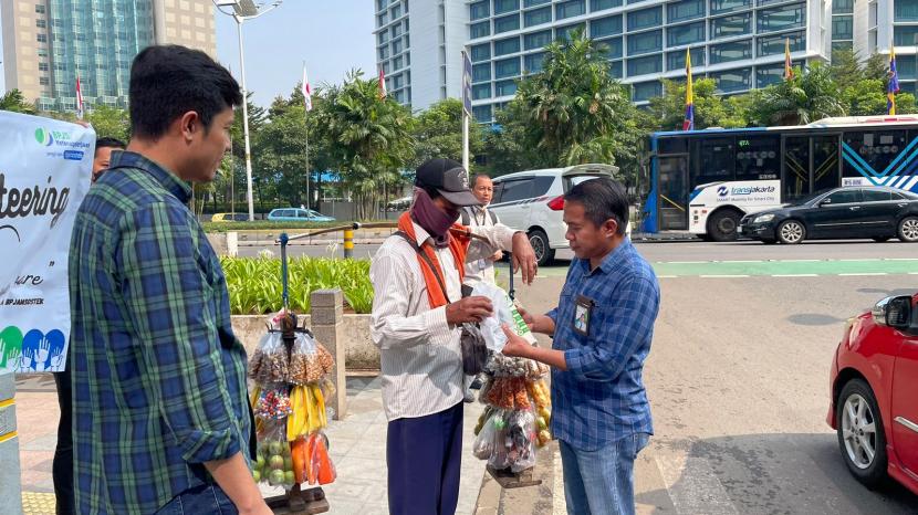 Kepala BP Jamsostek Jakarta Sudirman Suhuri membagikan tumblr dan paket sarapan kepada pedagang  di sekitar Mayapada Tower Jakarta.