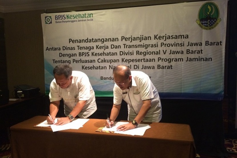 Kepala BPJS Kesehatan Divisi Regional V Jawa Barat Mohammad Edison (kiri) menandatangani kesepakatan kerja dengan Kepala Dinas Tenaga Kerja dan Transmigrasi Provinsi Jawa Barat Ferry Sofwan Arif di Kota Bandung, Rabu (19/4).