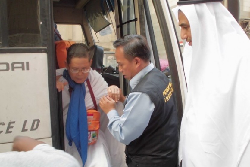 Kepala Daerah Kerja Makkah, Arsyad Hidayat membantu jamaah haji turun dari bus.