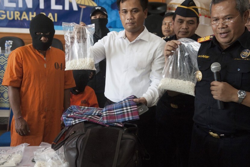 Kepala Direktorat Jenderal Bea Cukai Bali, NTB dan NTT Syarif Hidayat (kanan) dan polisi memperlihatkan barang bukti kokain yang dibawa tersangka INA (kiri) dalam konferensi pers di Kantor Bea Cukai Ngurah Rai, Denpasar, Senin (26/3).