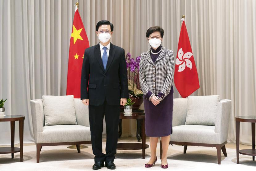 Kepala Eksekutif terpilih Hong Kong John Lee, kiri, dan Kepala Eksekutif Carrie Lam berpose untuk foto selama pertemuan di Kompleks Pemerintah Pusat menjelang konferensi pers di Hong Kong, Senin, 9 Mei 2022.