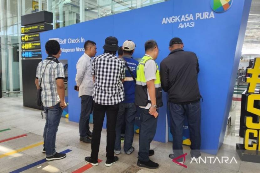 Kepala Kantor Otoritas Bandara Wilayah II Medan Sokhib Al Rokhman (kedua kanan) mengedukasi pemudik menggunakan self check-in di Bandara Internasional Kualanamu, Deli Serdang, Sumatera Utara, Senin (8/4/2024). 