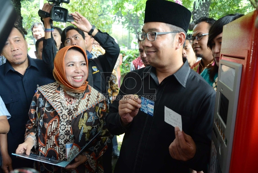 Kepala Perwakilan Bank Indonesia (BI) Jabar Rosmaya Hadi (berkerudung) dan Wali Kota Bandung Ridwan Kamil (berpeci) memegang kartu 'Bandung Smart Card' untuk pembayaran parkir pada launcing 'Bandung Smart Card' di halaman Gedung BI Jabar, Jl Braga, Kota Ba