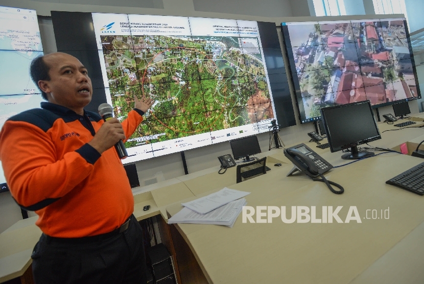 Kepala Pusat Data, Informasi, dan Humas Badan Penanggulangan Bencana (BNPB) Sutopo Purwo Nugroho lokasi bencana gempa di Provinci Aceh melalui layar di ruang pemantauan bencana Gedung BNPB, Jakarta, Jumat (9/12). BNPB mengklarifikasi jumlah korban meningga