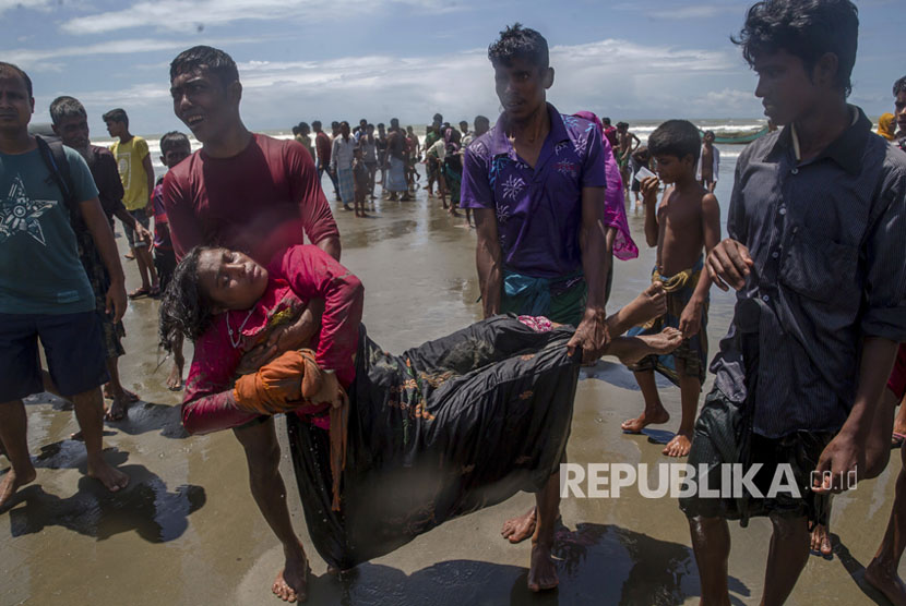Kerabat membawa seorang wanita Muslim Rohingya, yang jatuh pingsan saat kapal yang dia tumpangi berbaris beberapa menit sebelum mencapai pantai, menuju pusat perawatan medis di Shah Porir Dwip, Bangladesh, Kamis, (14/9).